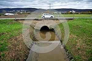 German people driving eco car on street road crossing irrigation canal and view landscape rural countryside farmland plantation at