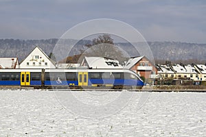 German regional train against the backdrop of houses and forest