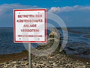 German sign saying "Do not enter the coastal protection system", standing on the shore.