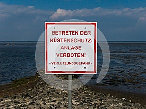 German sign saying "Do not enter the coastal protection system", standing on the shore.