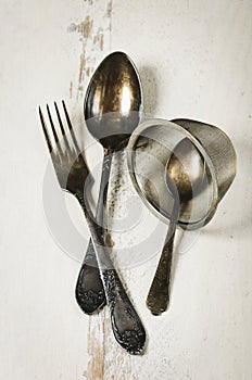German silver spoon, fork and other utensils on a white wooden b