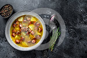 German Split pea soup with smoked sausages and meat. Black background. Top view. Copy space