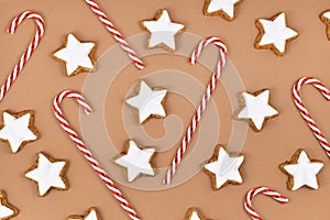 German star shaped glazed Christmas cookies called `Zimtsterne` and candy canes on brown background