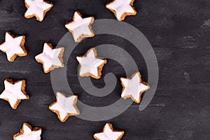 German star shaped glazed cinnamon Christmas cookies called `Zimtsterne` on black ackground