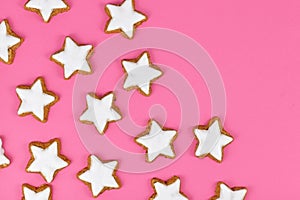 German star shaped glazed cinnamon Christmas cookies called `Zimtsterne` on pink background