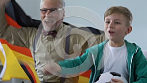 German supporters celebrating team victory, boy with grandpa watching football
