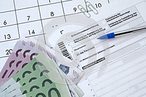 German tax form with pen and european money bills lies on office calendar. Taxpayers in Germany using euro currency to pay taxes