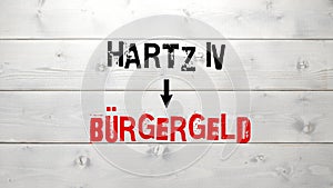 German text Harz4 to Buergergeld on white grey aged wooden background
