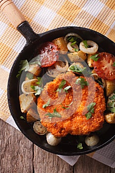 German Weiner schnitzel with vegetables in a pan closeup. Vertic