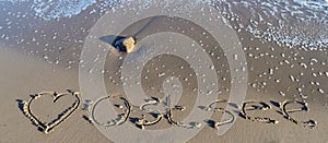 The german word Ostsee Baltic Sea and a heart written into the sand of the beach