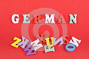 German word on red background composed from colorful abc alphabet block wooden letters, copy space for ad text. Learning english