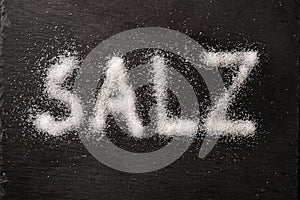 German word Salz meaning salt written with salt crystals on a dark slate, high angle view from above photo