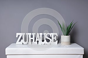 german word zuhause meaning at home as modern interior decoration next to potted plant