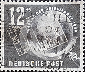 GERMANY, DDR - CIRCA 1949 : a postage stamp from Germany, GDR showing the black Bayern Einser from 1849 under a magnifying glass.