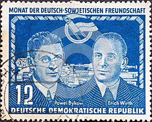GERMANY, DDR - CIRCA 1950: a postage stamp from Germany, GDR showing Pawel Bykow fast movers and Erich Wirth in front of the sym