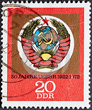 GERMANY, DDR - CIRCA 1972: a postage stamp from Germany, GDR showing the emblem of the USSR with hammer and sickle on red postal s