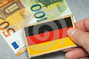 Germany euro money, Germany financial and economic situation, German flag held in hand against a background of 50 and 100 euro