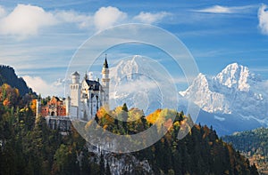 Germany. The famous Neuschwanstein Castle in the background of snowy mountains and trees with yellow and green leaves. photo