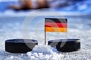 Německá vlajka na párátko mezi dvěma hokejovými puky. Německo bude hrát na mistrovství světa ve skupině A. 2019 IIHF World