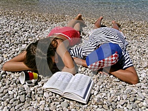 Germany girl and Croatian boy lying on stone beach