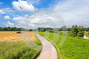 Germany rural landscape with river and wheat field after harvesting. A farm tractor cultivating a harvested field