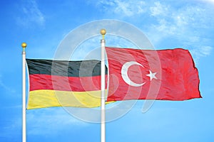 Germany and Turkey two flags on flagpoles and blue cloudy sky