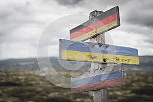 germany ukraine russia flag on wooden signpost outdoors in nature.