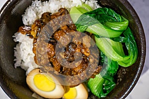 Geschmortes Schweinefleisch, Entenei, Bok Choy GemuÌˆse und Reis als Taiwainesische Reis-Bowl in einer schwarzen Keramikschale