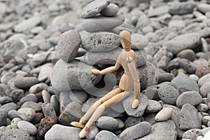 Gestalt`s wooden man sits next to a pyramid of stones