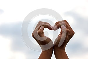 Gesture hands heart of on backdrop of the sky