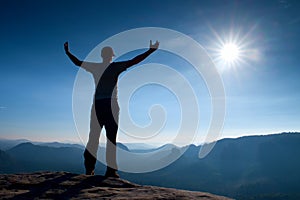 Gesture of triumph. Happy hiker in sportswear. Tall man on the peak of sandstone rock in national park Saxony Switzerland watch do