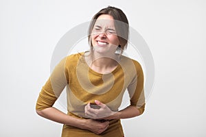Gesture of young european woman having terrible stomach pain