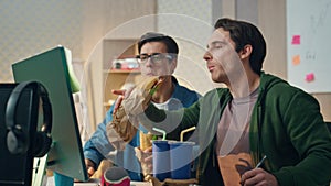 Gesturing colleagues having lunch looking monitor. Closeup coworkers pointing