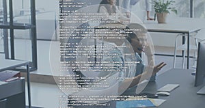 Gesturing man in button-down shirt explaining code on monitor at open office, with code overlay