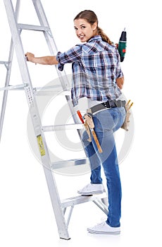 Get back to work. Studio shot of a cute young handy woman standing by a ladder holding a drill and looking over her