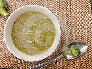 Get better soon written in vegetable soup with spoon