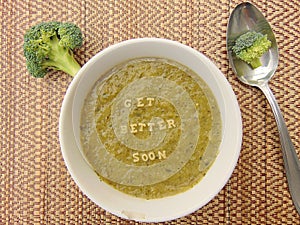 Get better soon written in vegetable soup with spoon photo