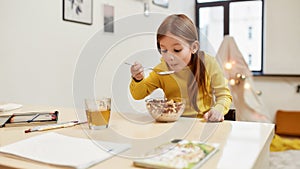 Get Cereals and become stronger. Caucasian cute little girl eating cereal balls with milk for her breakfast or lunch