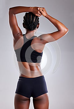 Get fit instead of admiring other peoples body. Rearview shot of a sporty young woman stretching her arms against a grey