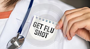 Get Flu Shot text on white card in hand doctor taking it out of his pocket.