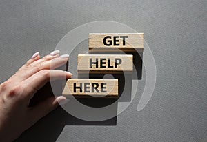 Get help here symbol. Wooden blocks with words Get help here. Beautiful grey background. Businessman hand. Business and Get help