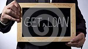 Get a loan written on blackboard, businessman holding sign, business concept