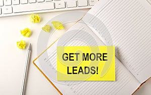 GET MORE LEADS text on sticker on the diary with keyboard and pencil