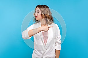 Get out! Portrait of mad bossy woman pointing to the side and turning away with angry vexed face. blue background