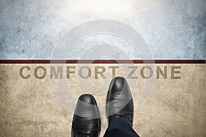 Get out of your comfort zone. Comfort Zone Concept, Male with Leather Shoes Steps over a word with line on Concrete Floor, Top