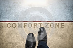 Get out of your comfort zone. Comfort Zone Concept, Male with Leather Shoes Steps over a word with line on Concrete Floor, Top photo