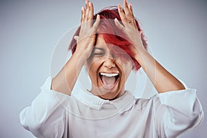Get out of your own head. Studio shot of an attractive young woman screaming against a gray background.