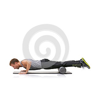 Get through the pain to see great results. A young man doing push-ups on his exercise mat with his legs raised by a foam