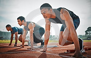 Get set. Full length shot of three handsome young male athletes starting their race on a track.