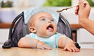 Get that spoon over here. a mother feeding her adorable baby boy.